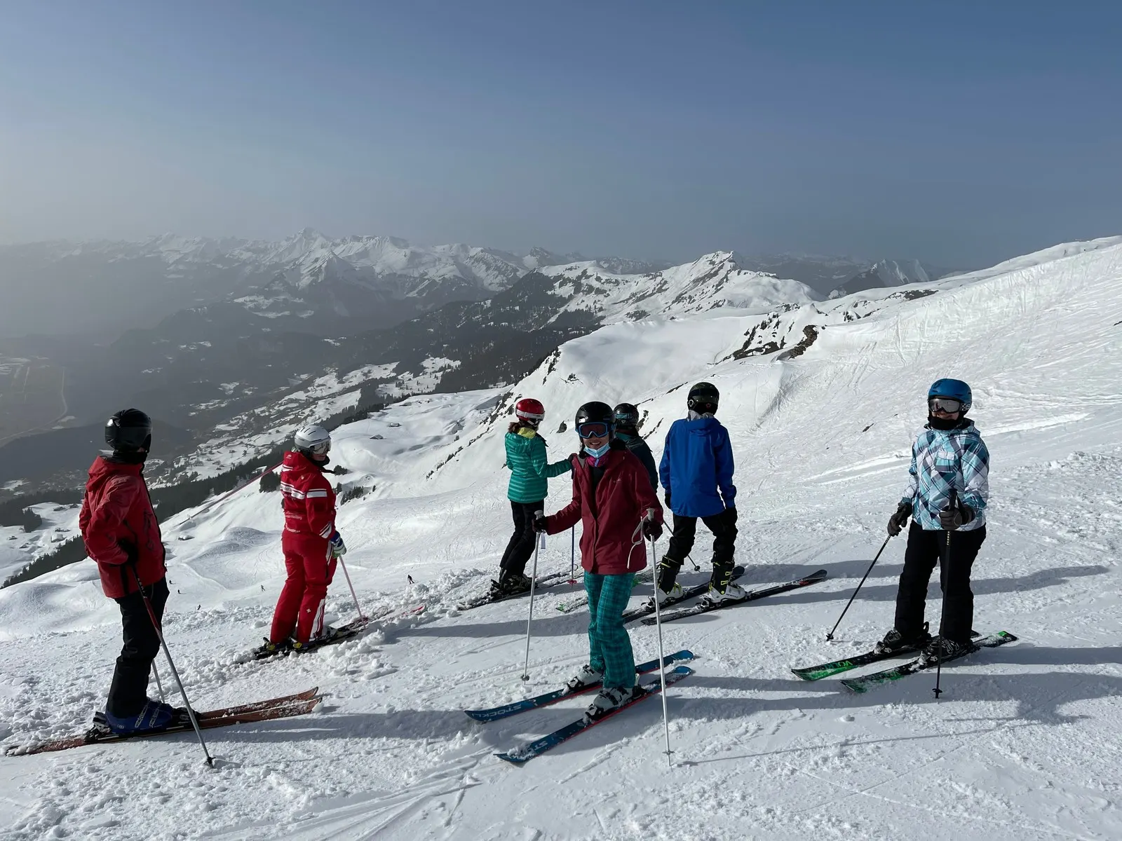 Helmeted skiers with skis and poles on a snowy piste above Hasliberg, Switzerland, illustrative image