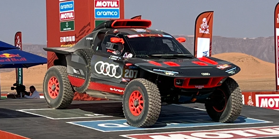Mattias Ekström's black and red Audi rally car on the Dakar start podium in 2024